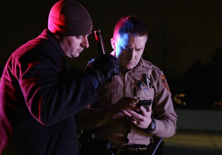 In this photo taken Dec. 23, 2010, St. Louis County police officers Frank Haus, left, and Andrew Huskey use a cellular phone to pull up records of pseudoephedrine sales in real time during a traffic stop in Fenton, Mo. Police are using the information to track profiteers who buy over-the-counter medications containing pseudoephedrine and sell them to meth producers at a huge markup. (AP Photo/Jeff Roberson)